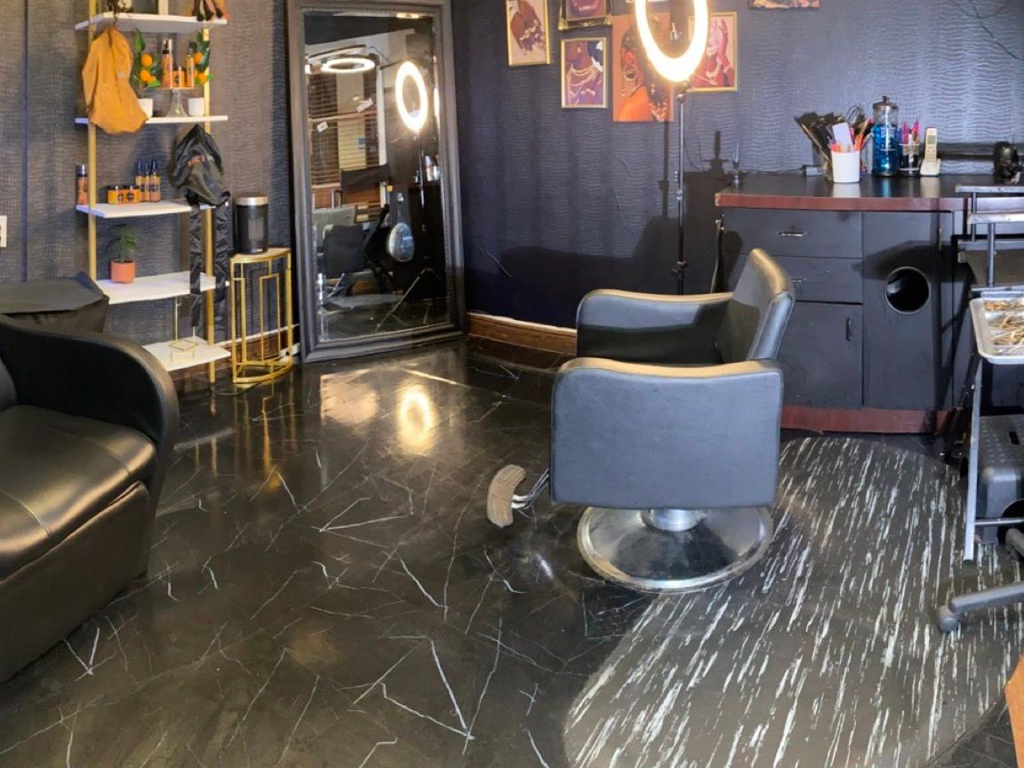 Dark luxe salon suite with marble floors, ring lights, and styling chairs
